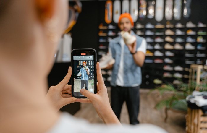 Person filming a shoe shopping experience in a trendy store using a smartphone.