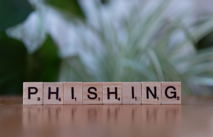 Wooden tiles spelling 'phishing' highlight cybersecurity themes.
