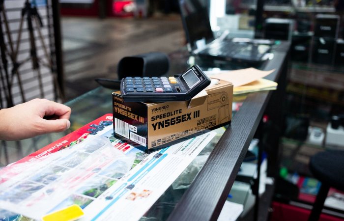 Close-up of a payment terminal and camera flash box on a store counter.