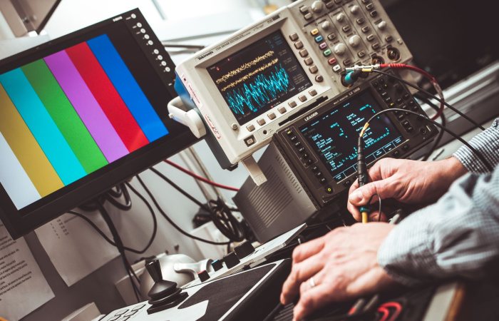 Technician operating laboratory electronic testing and measurement devices with colorful display.